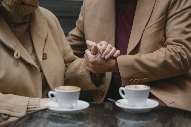Warm moment of two people holding hands over coffee